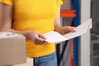 Photo of Post office worker with envelopes indoors, closeup