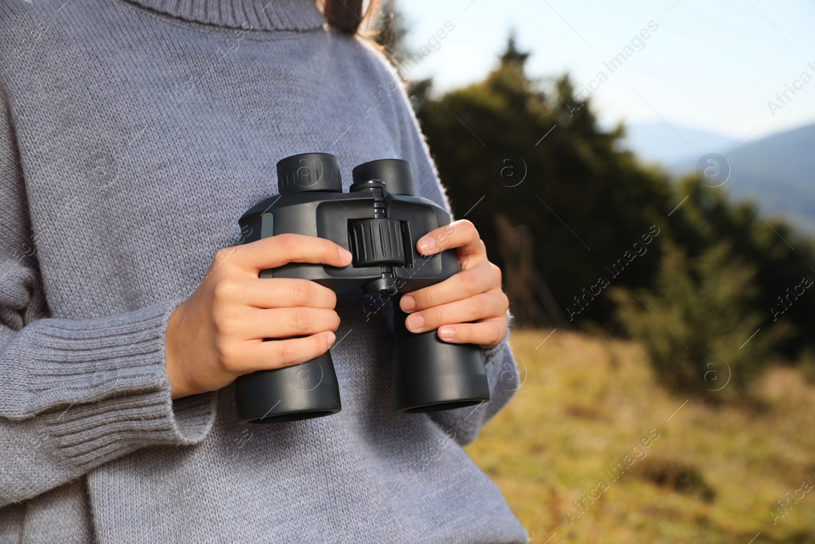 Photo of Woman with binoculars in mountains on sunny day, closeup. Space for text