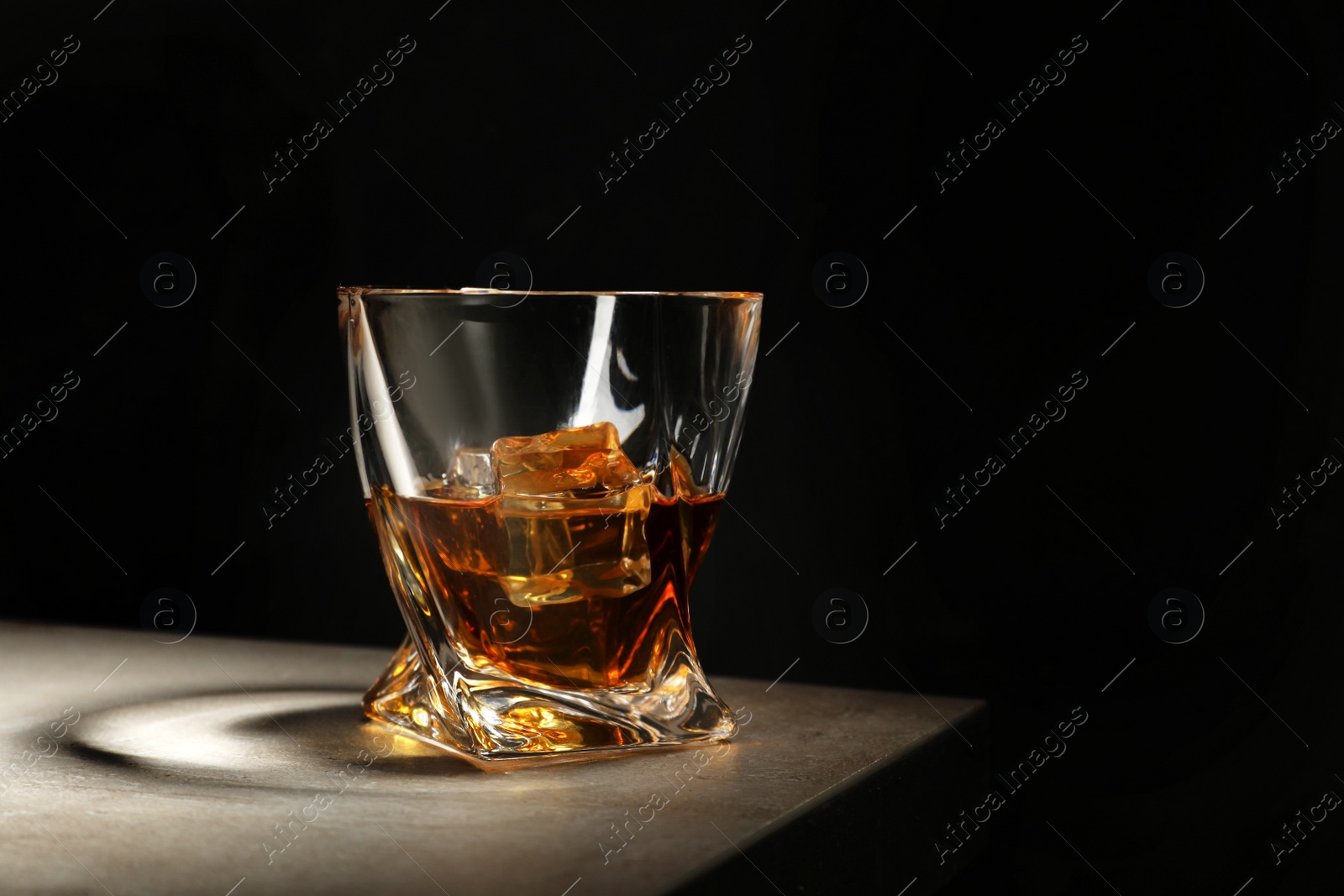 Photo of Golden whiskey in glass with ice cubes on table. Space for text