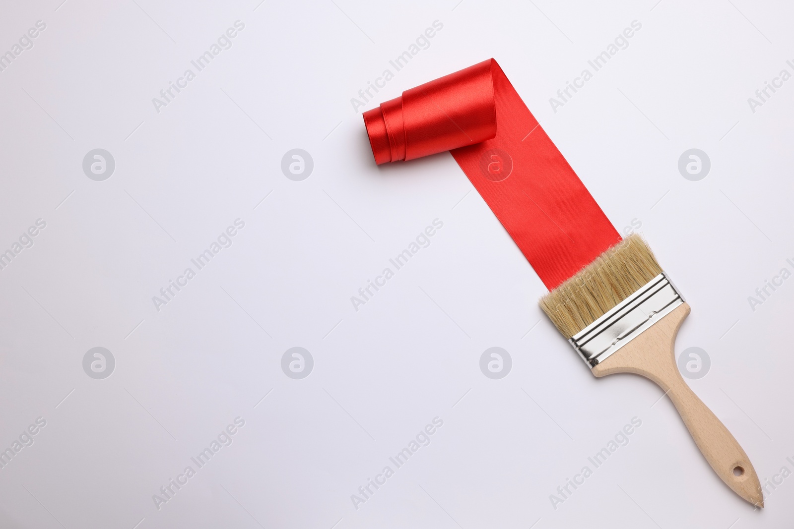 Photo of Brush painting with red ribbon on light background, top view. Space for text. Creative concept