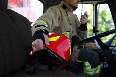 Photo of Firefighter using portable radio set while driving fire truck, selective focus