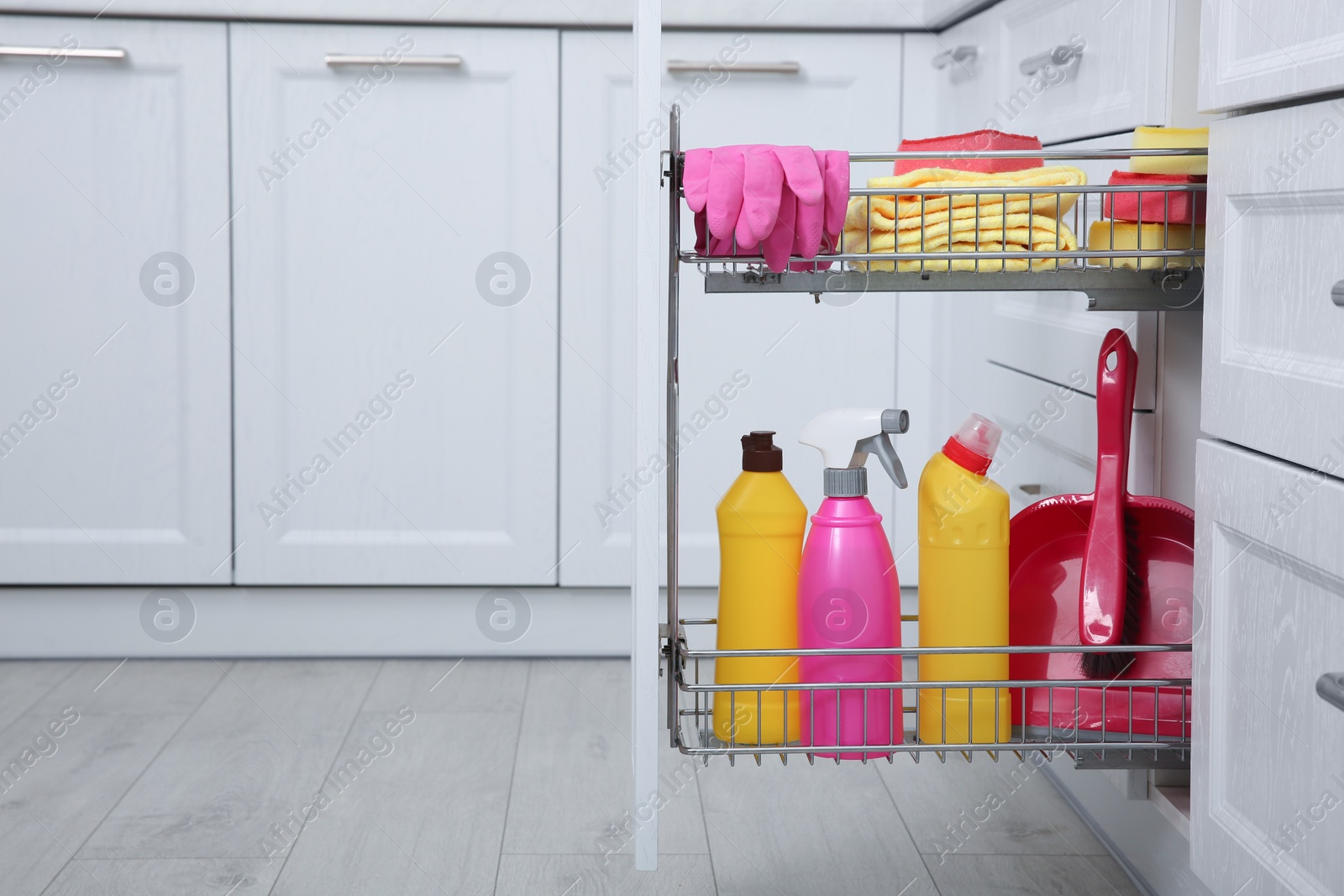 Photo of Open drawer with different cleaning supplies in kitchen. Space for text