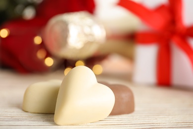 Photo of Tasty heart shaped chocolate candies on white wooden table, closeup. Valentine's day celebration