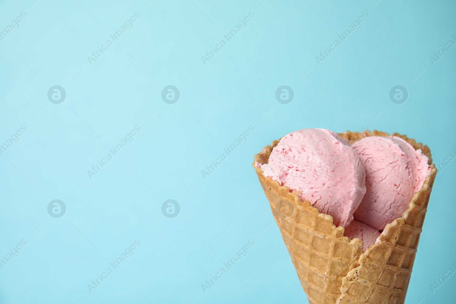 Photo of Delicious ice cream in waffle cone on color background, space for text