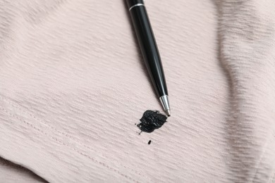 Photo of Pen and stain of black ink on beige shirt, closeup. Space for text