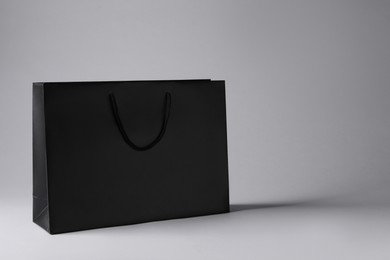 Black paper bag on light grey background, space for text