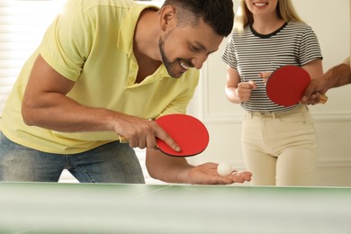 Photo of Happy man playing ping pong with friends indoors