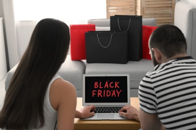 Couple using laptop with Black Friday announcement on screen at table