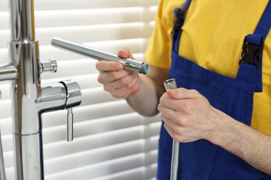 Photo of Plumber repairing metal faucet in bathroom, closeup