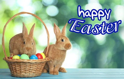 Image of Happy Easter. Adorable bunnies and wicker basket with eggs on wooden table outdoors