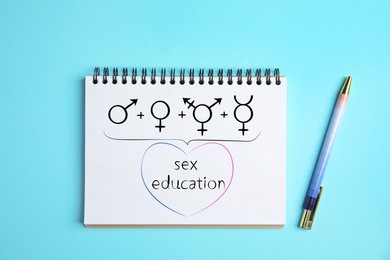 Image of Notebook with text Sex Education, male, female, transgender and gender fluid signs on light blue background, top view