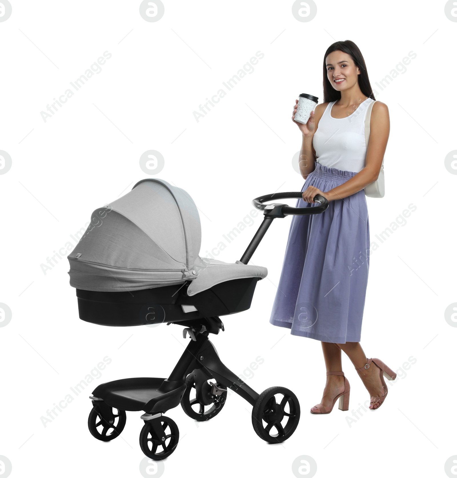 Photo of Happy young woman with cup of drink and baby stroller on white background