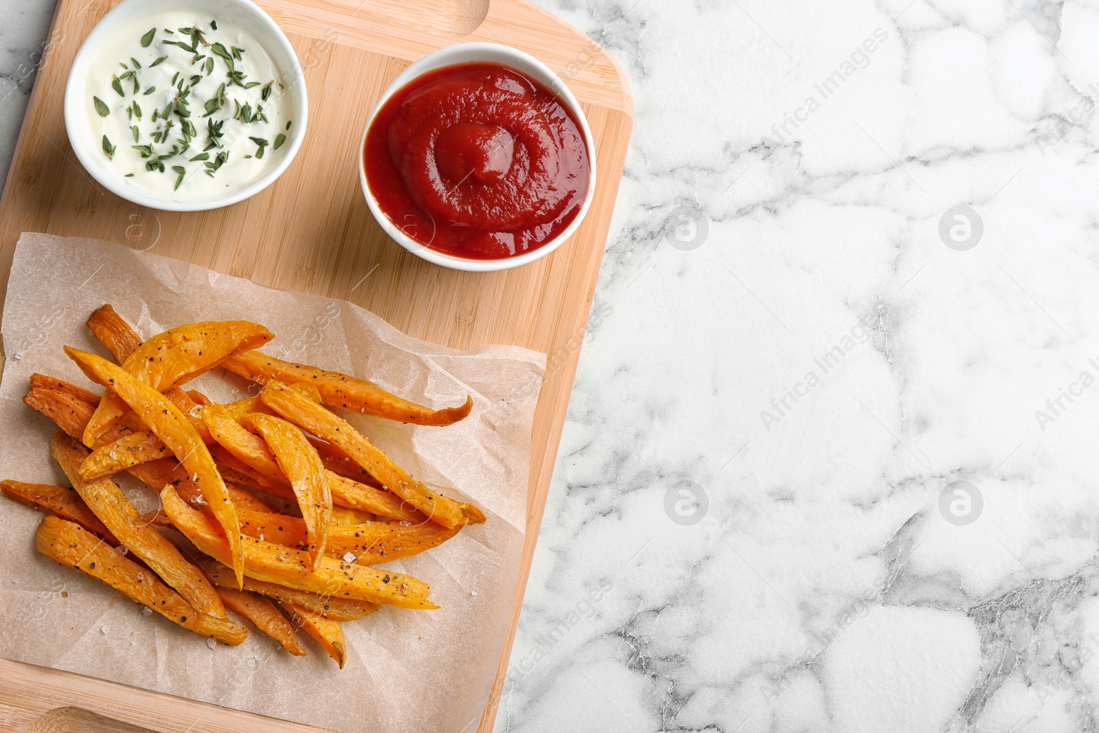 Photo of Board with sweet potato fries and sauces on marble background, top view. Space for text