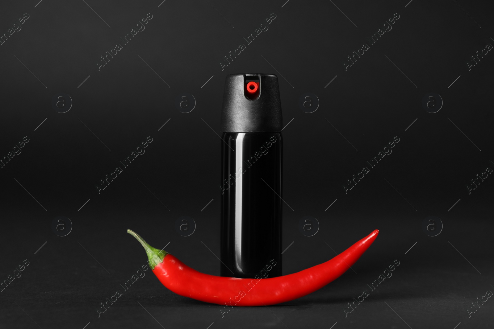 Photo of Bottle of gas spray and fresh chili pepper on black background