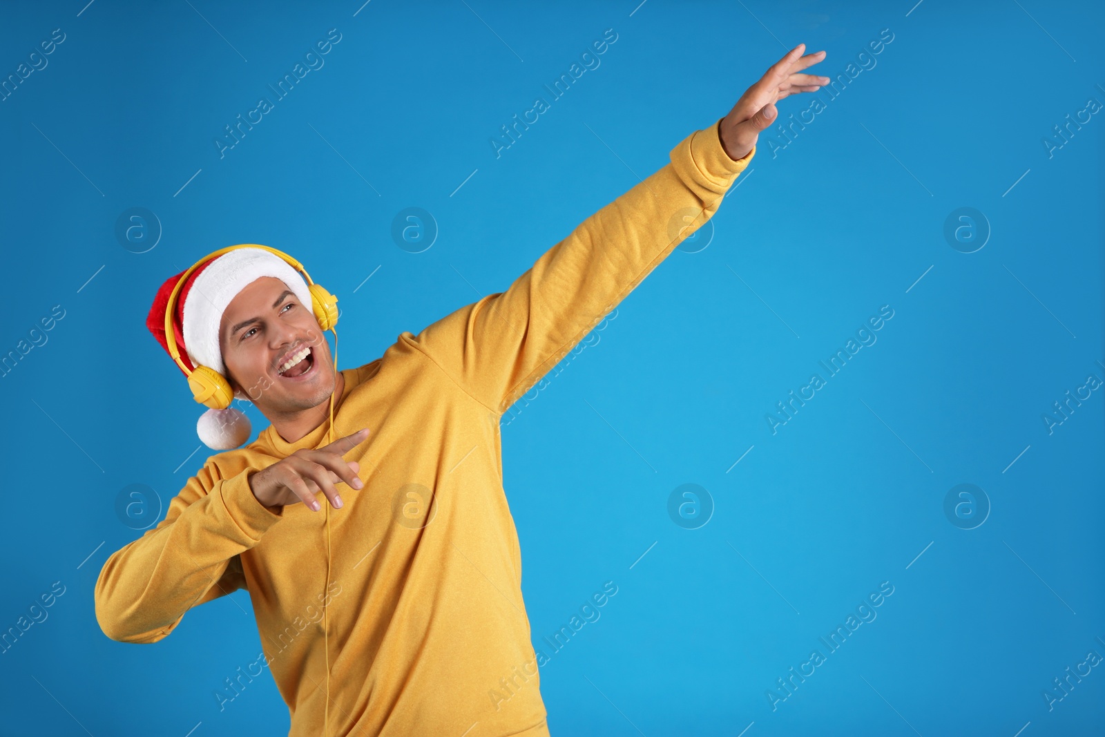 Photo of Emotional man with headphones on blue background, space for text. Christmas music