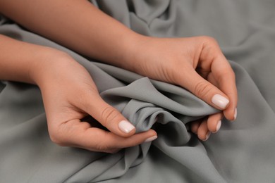 Photo of Woman touching smooth grey fabric, closeup view