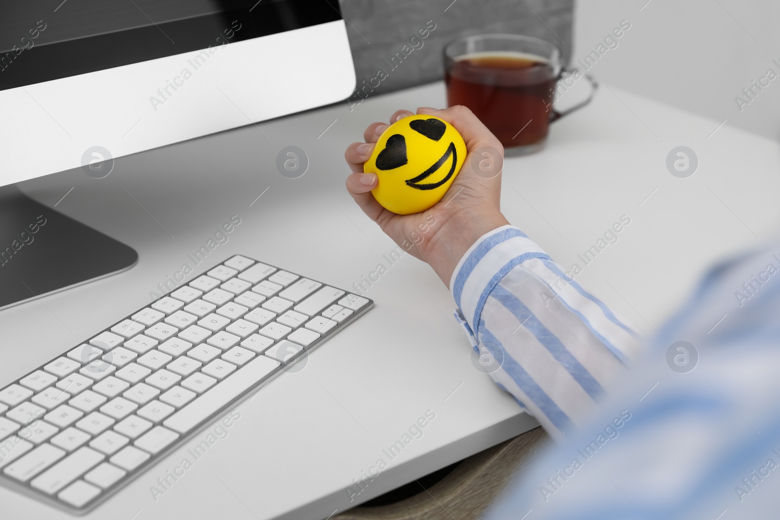 Photo of Woman squeezing antistress ball at workplace, closeup