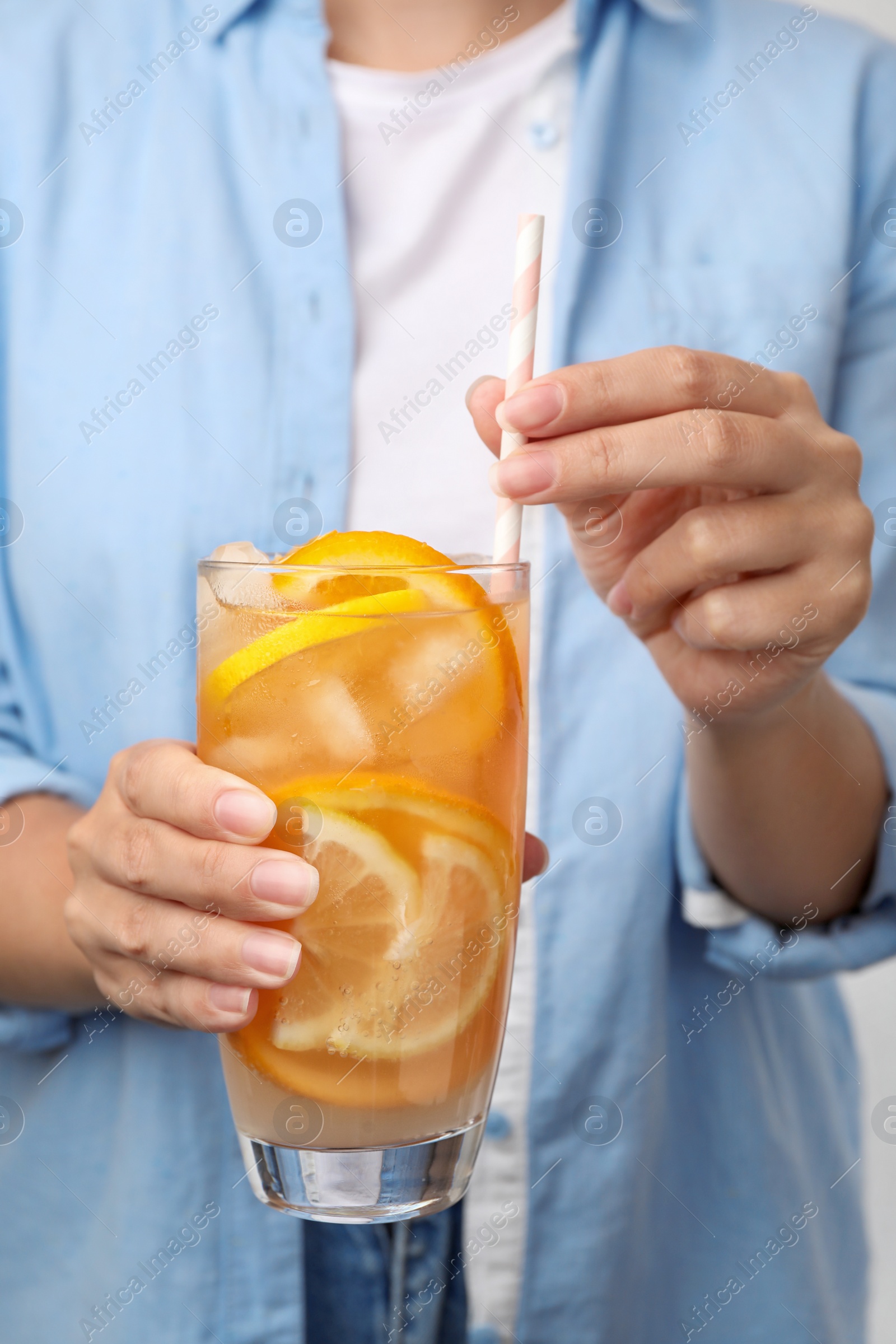 Photo of Woman holding glass of orange refreshing drink with straw, closeup