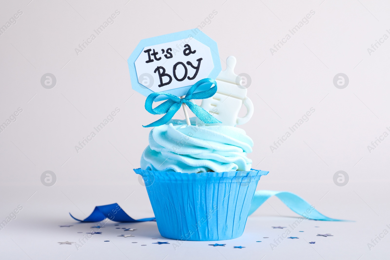 Photo of Beautifully decorated baby shower cupcake for boy with cream and topper on light background