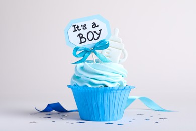 Beautifully decorated baby shower cupcake for boy with cream and topper on light background