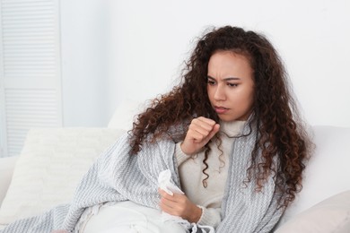 Sick African American woman coughing at home