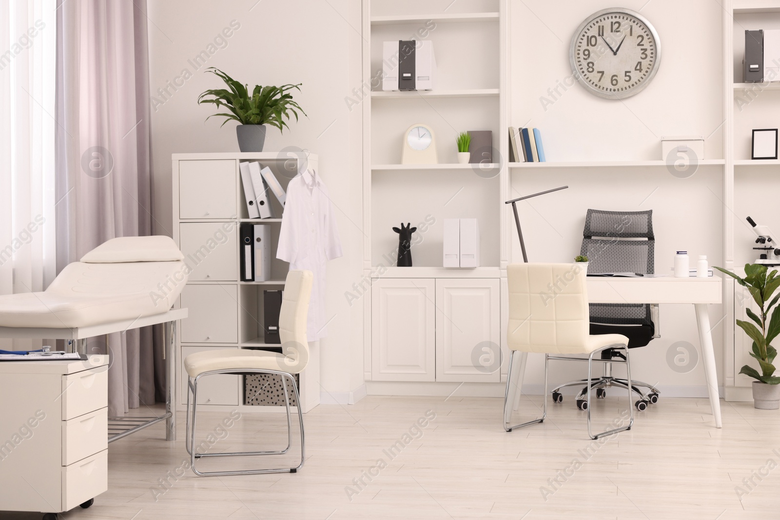 Photo of Modern medical office interior with doctor's workplace and examination table