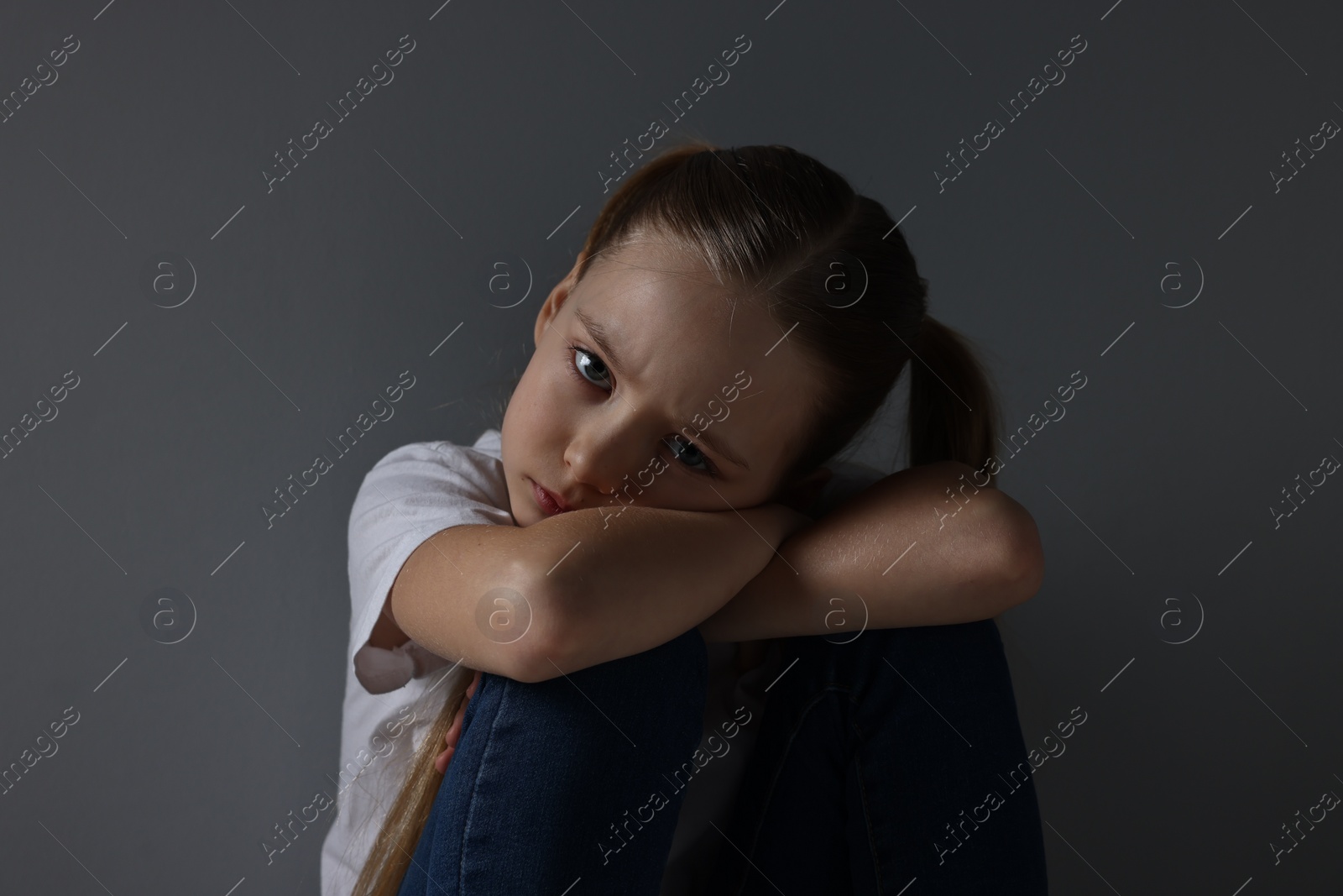 Photo of Sad girl sitting near dark grey background