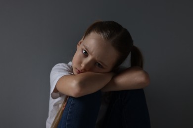 Photo of Sad girl sitting near dark grey background