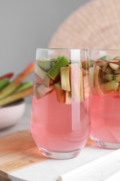 Photo of Glasses of tasty rhubarb cocktail on table, closeup
