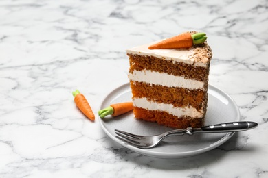 Piece of sweet carrot cake with delicious cream on white marble table. Space for text