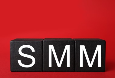 Photo of Black cubes with abbreviation SMM (Social media marketing) on red background