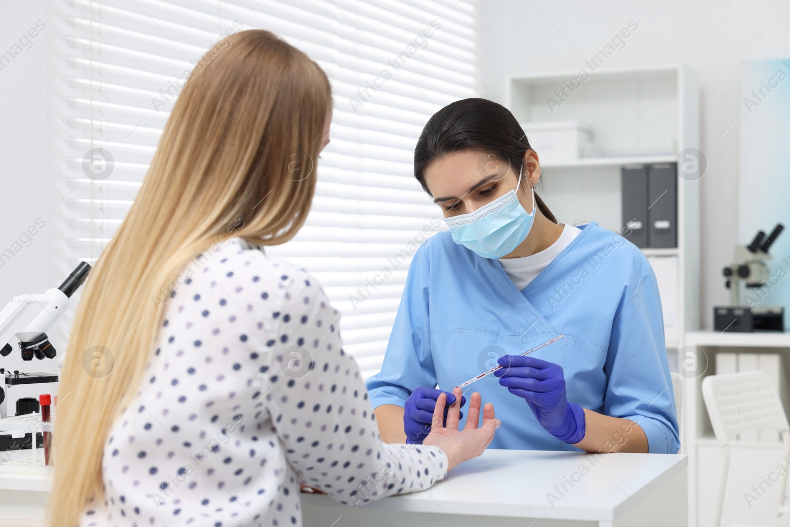 Photo of Laboratory testing. Doctor taking blood sample from patient at white table in hospital