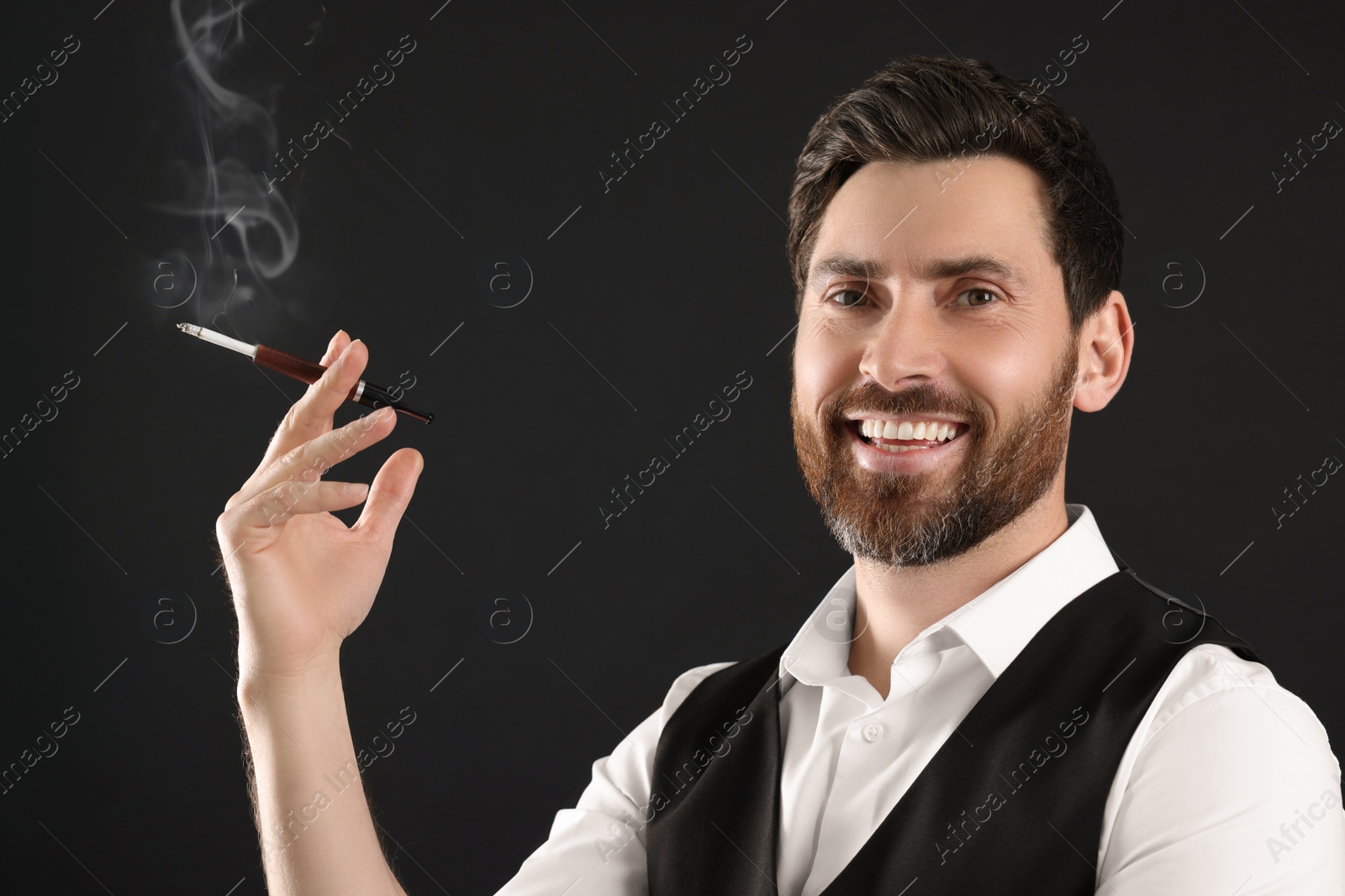 Photo of Man using cigarette holder for smoking on black background