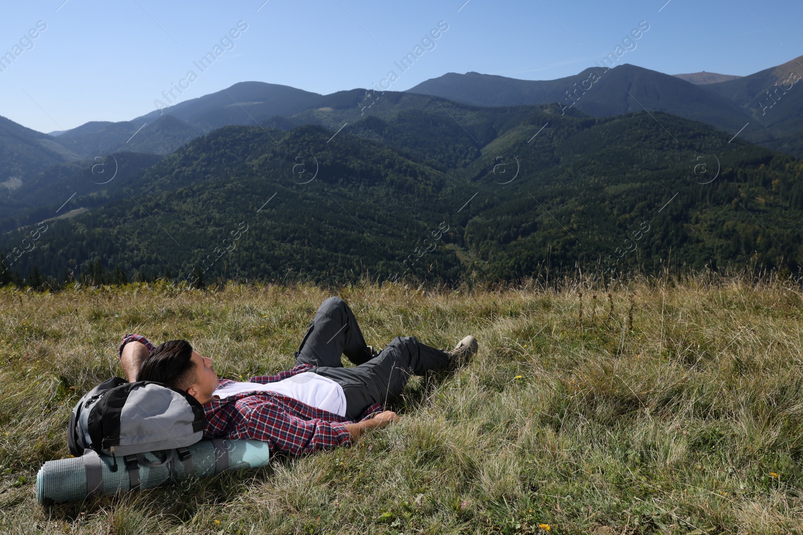 Photo of Tourist with backpack resting on ground in mountains