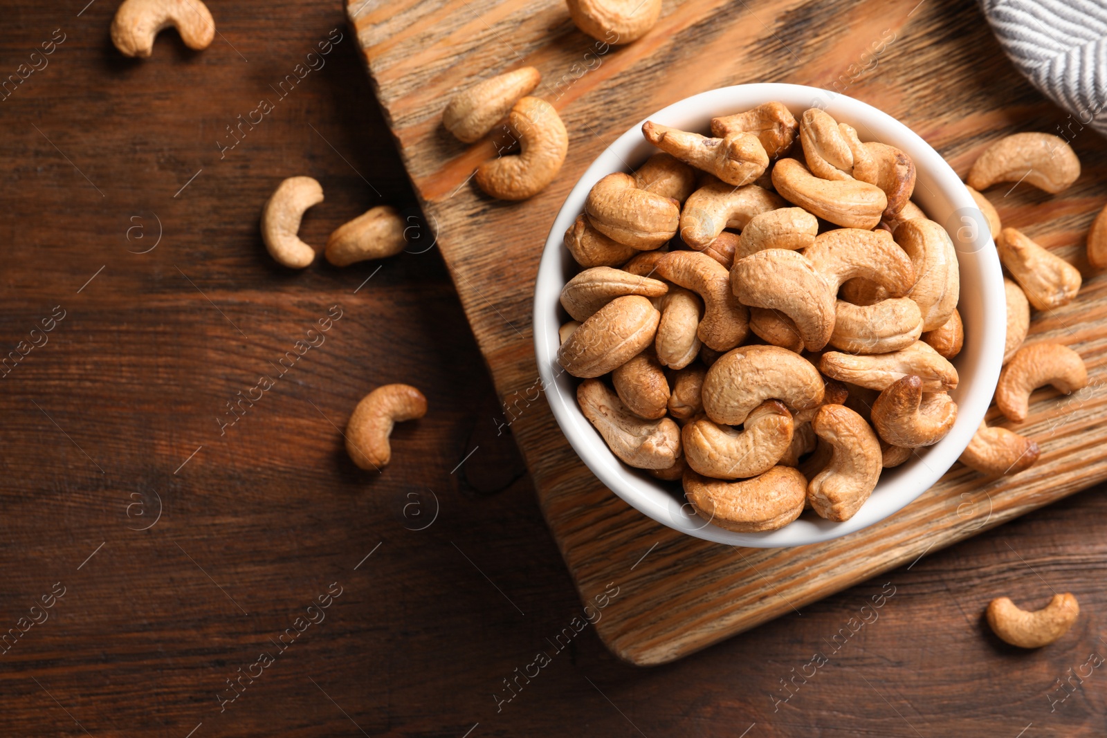 Photo of Tasty cashew nuts in bowl on wooden table, top view