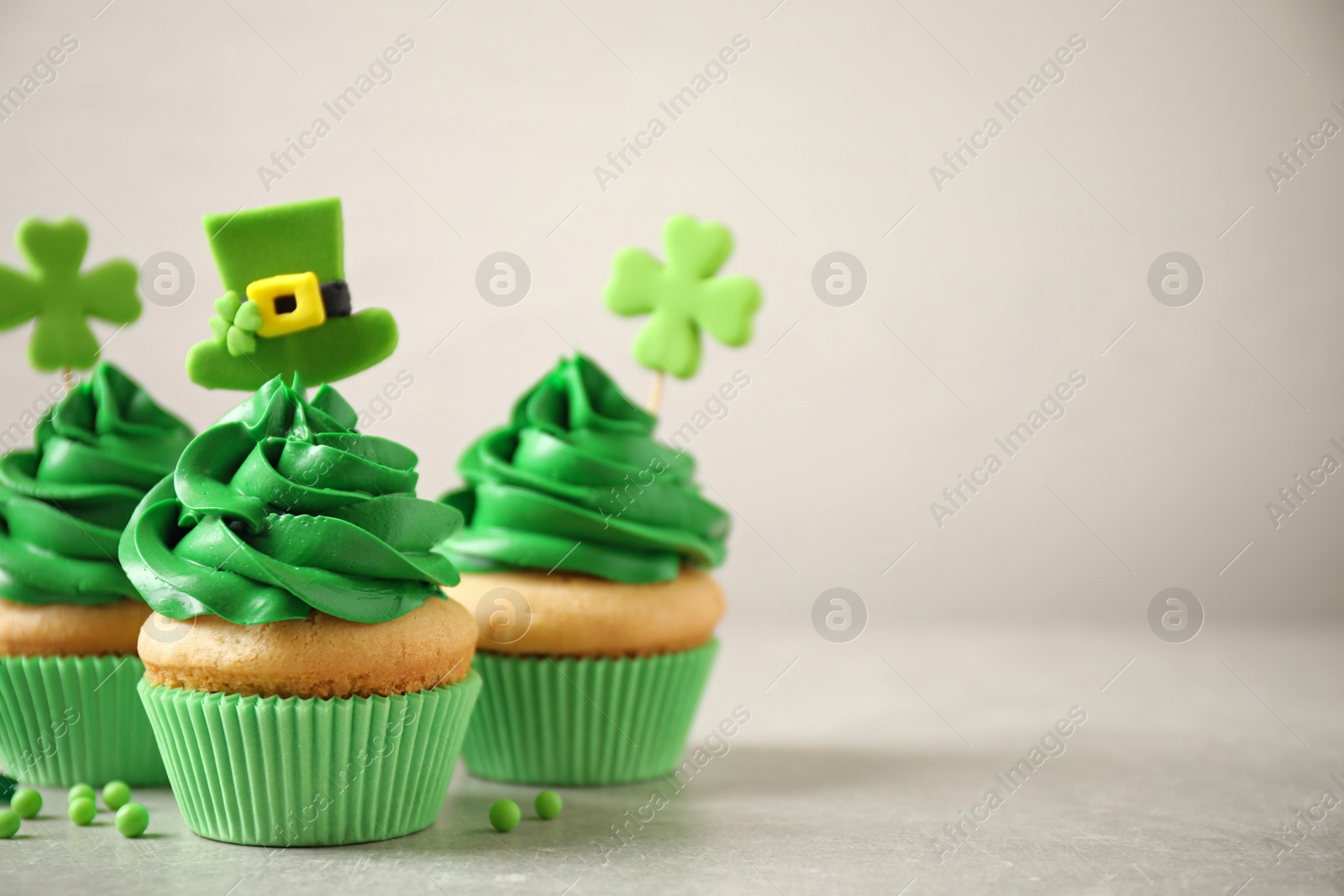 Photo of Delicious decorated cupcakes on light table, space for text. St. Patrick's Day celebration