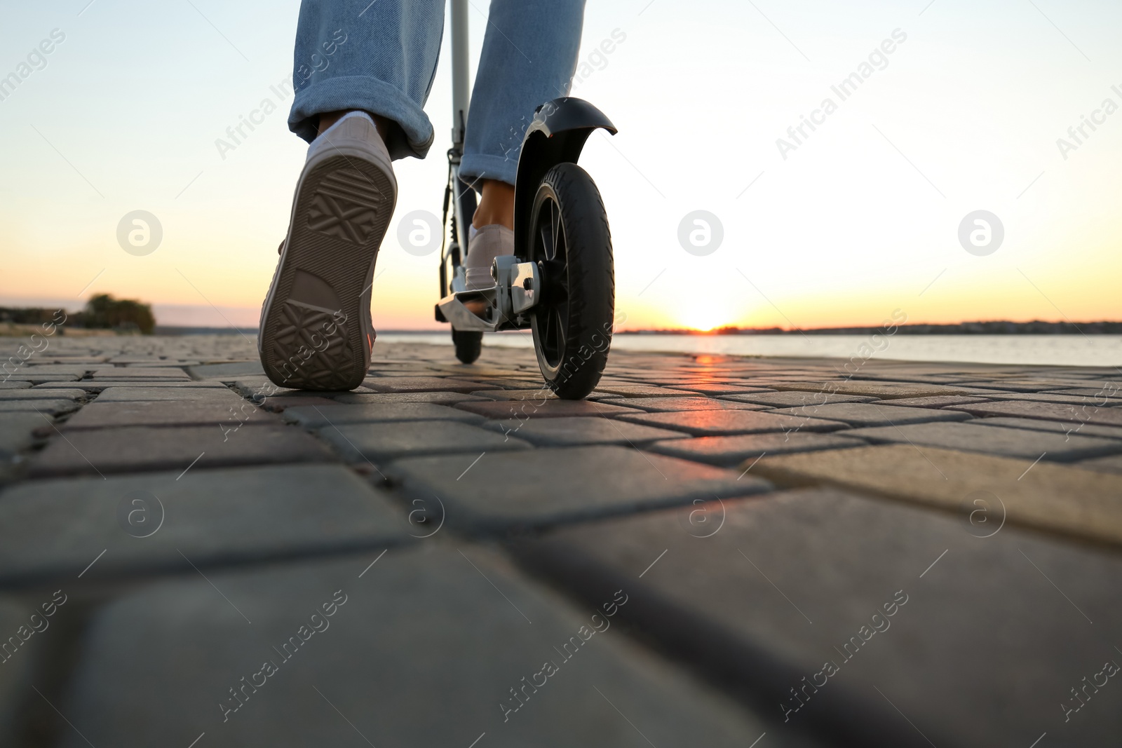 Photo of Woman riding modern kick scooter along street, closeup