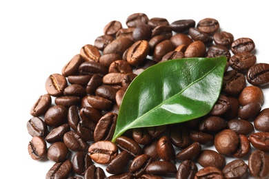 Photo of Roasted coffee beans and green leaf on white background, closeup