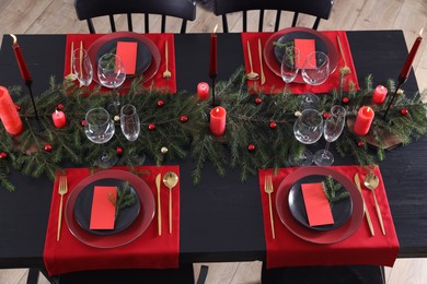 Elegant Christmas table setting with burning candles, decor and place cards for festive dinner, above view