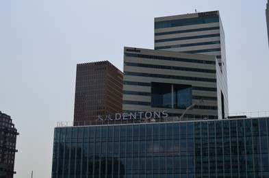 Photo of Amsterdam, Netherlands - June 18, 2022: Building with Dentons logo against blue sky