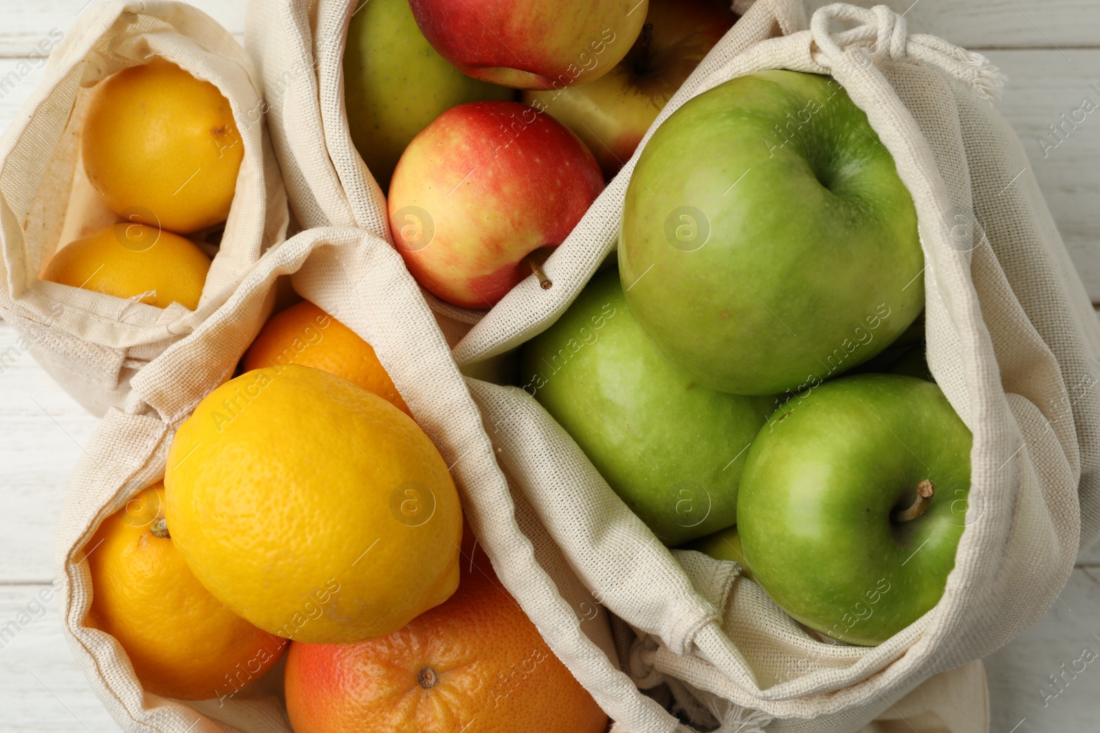 Photo of Cotton eco bags with fruits, closeup view