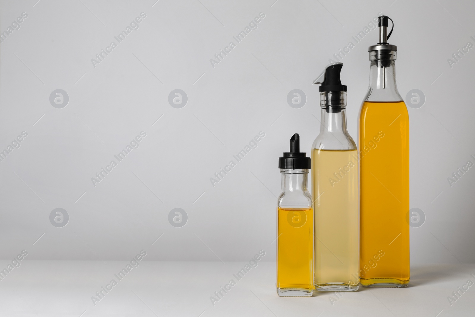 Photo of Bottles of different cooking oils on white background, space for text