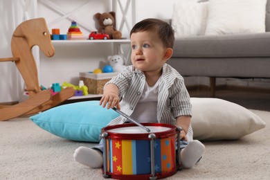 Photo of Cute little boy playing toy drum at home