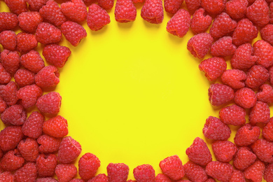 Photo of Frame of delicious ripe raspberries on yellow background, flat lay. Space for text