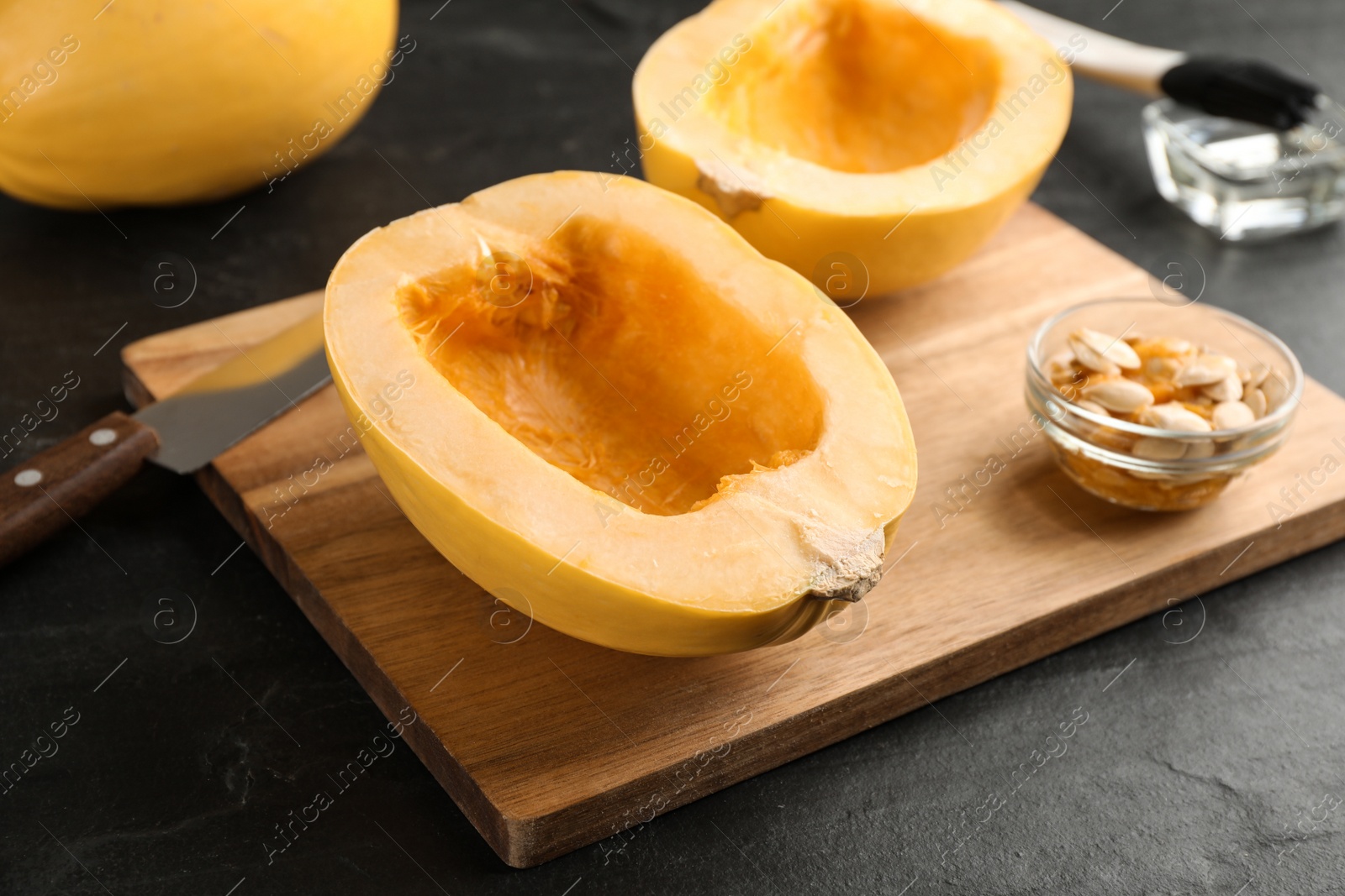 Photo of Halves of fresh spaghetti squash on black table. Cooking vegetarian dish