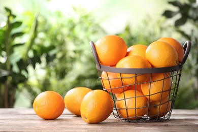 Basket and fresh oranges on wooden table. Space for text