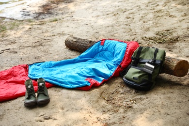Photo of Sleeping bag, backpack with cup and boots on beach