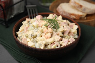 Photo of Tasty Olivier salad with boiled sausage in bowl on table, closeup