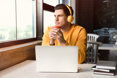 Man listening to audiobook at table in cafe