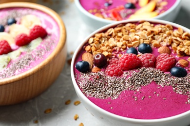 Acai smoothie bowls with granola and berries on marble table